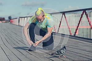 The man on the bridge ties his sneaker before jogging