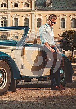 Man with briefcase near classic convertible