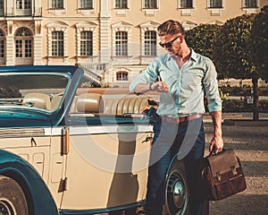 Man with briefcase near classic convertible
