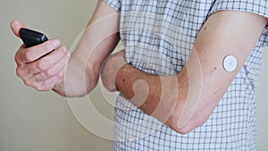 A man brings to the hand the reading device to the sensor for measuring glucose