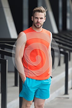 Man with bristle on serious face in sporty wear, urban background. Sport fashion concept. Guy bearded and attractive
