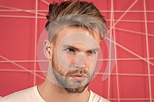 Man with bristle on strict concentrated face, pink background. Masculinity concept. Guy bearded and attractive with