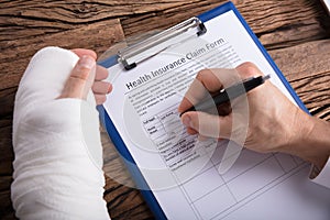 Man With Broken Arm Filling Health Insurance Claim Form