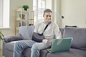 Man with Broken Arm Using Laptop on Living Room Sofa