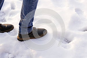Man in brown boots and blue jeans desided to make first step to obscurity on the snow. Copy space. First step after snow