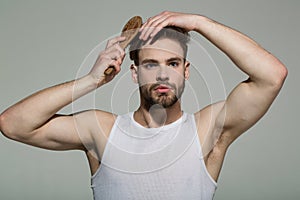 Man brush hair with hairbrush on grey background