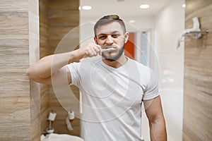 Man brushes his teeth in bathroom, morning hygiene