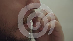 Man brushes his teeth with dental floss.