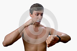 Man brushing his teeth also looks on at watch on white background