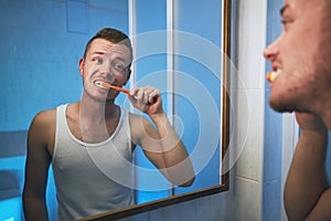 Man brushing teeth in home bathroom