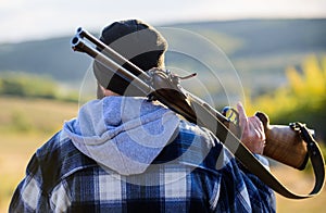 Man brutal guy gamekeeper in hat nature background. Brutality and masculinity. Hunter carry rifle gun on shoulder rear