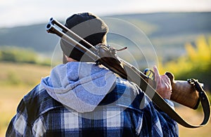 Man brutal guy gamekeeper in hat nature background. Brutality and masculinity. Hunter carry rifle gun on shoulder rear photo