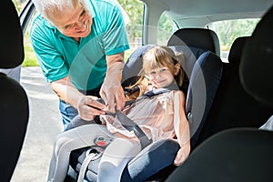 Grandfather Buckling Up On Granddaughter In Car Safety Seat photo