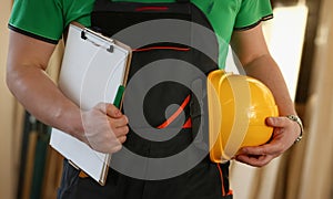 Man builder holding documents and safety helmet in his hands closeup