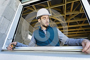 man builder infront window with tape measure
