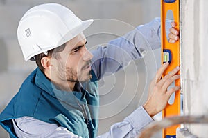 Man builder measuring level wall