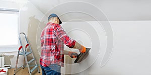 Man builder plastering a wall using a construction trowel. House renovation.