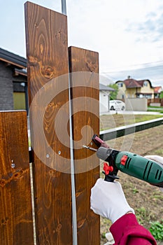 man building his own special wooden fence with driller