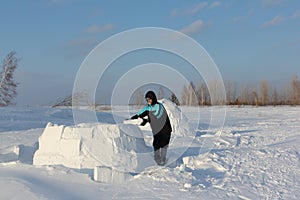 Man building an igloo of snow blocks in the winter