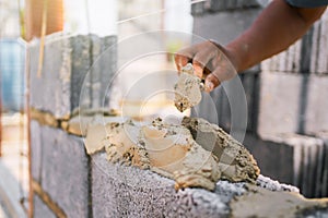 man is building a wall with a bucket of cement