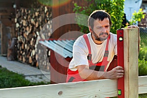 Man building a wooden fence - checking with a level