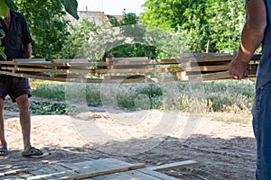 Man building a wooden fence. Workers pick up wooden boards for the fence formwork.