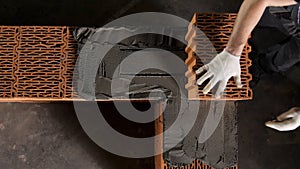 A man builds a brick wall, construction of a brick house. Stock footage. Top view of industrial worker placing ceramic