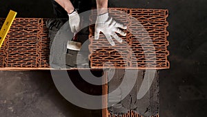 A man builds a brick wall, construction of a brick house. Stock footage. Top view of industrial worker placing ceramic