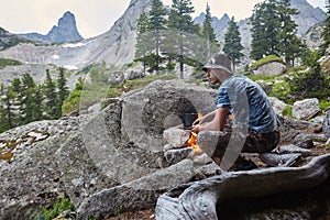 Man built a campfire in the woods in nature. Survive in the mountains in the forest, cooking in a pot pan over a campfire. Man in