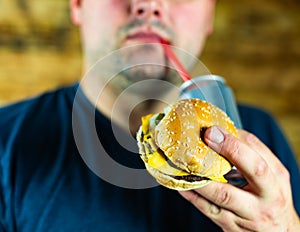 Man with burger and can of pop drink