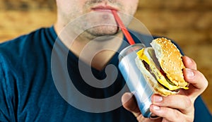 Man with burger and can of pop drink