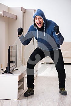 The man burglar stealing tv set from house