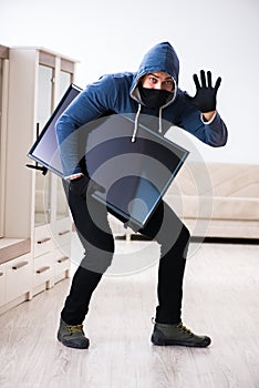 The man burglar stealing tv set from house