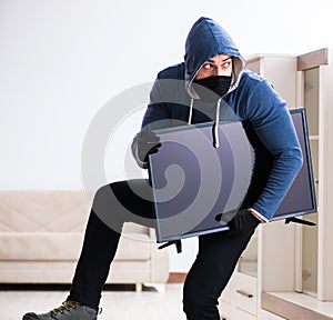 Man burglar stealing tv set from house