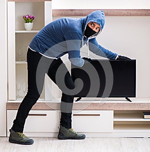 Man burglar stealing tv set from house