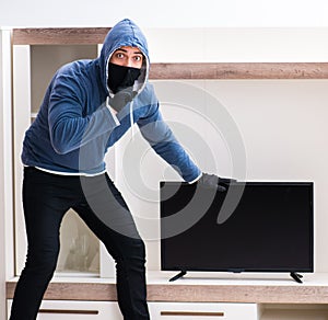 Man burglar stealing tv set from house