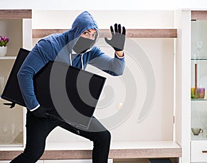 Man burglar stealing tv set from house