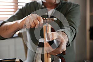 Man burnishing edges of leather belt in workshop photo