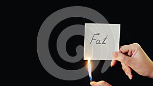 Man burns a paper with the inscription Fat