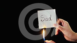 Man burns a paper with the inscription Sad