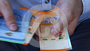 A man in a business shirt counting Malaysia money called Ringgit. Various banknotes