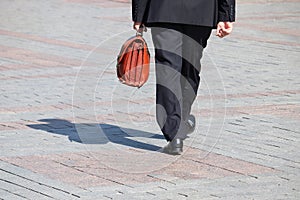 Man in a business suit carrying leather briefcase walking on the street