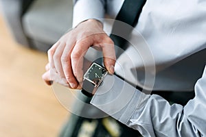 A man in a business suit checking a wrist watch on his hand