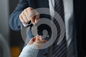 Man in business suit hands overing house keys to woman closeup