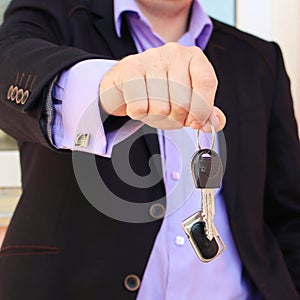 A man in a business suit holding key with remote control