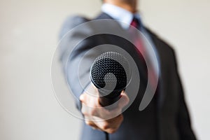 Man in business suit holding a microphone conducting a business