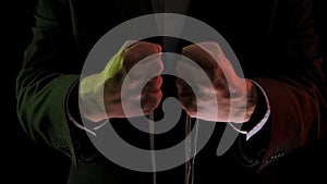 Man in business suit holding puppet ropes. Close up dictator hands holds strings for manipulation on black background