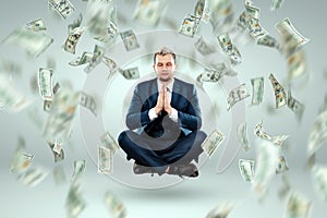 A man in a business suit levitates in the lotus position against the background of falling dollars, rain of money. Business