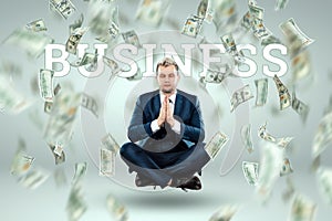 A man in a business suit levitates in the lotus position against the background of falling dollars, rain of money. Business