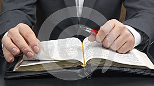 Man in a business suit reads the holy bible close-up. The study of religion and Christianity